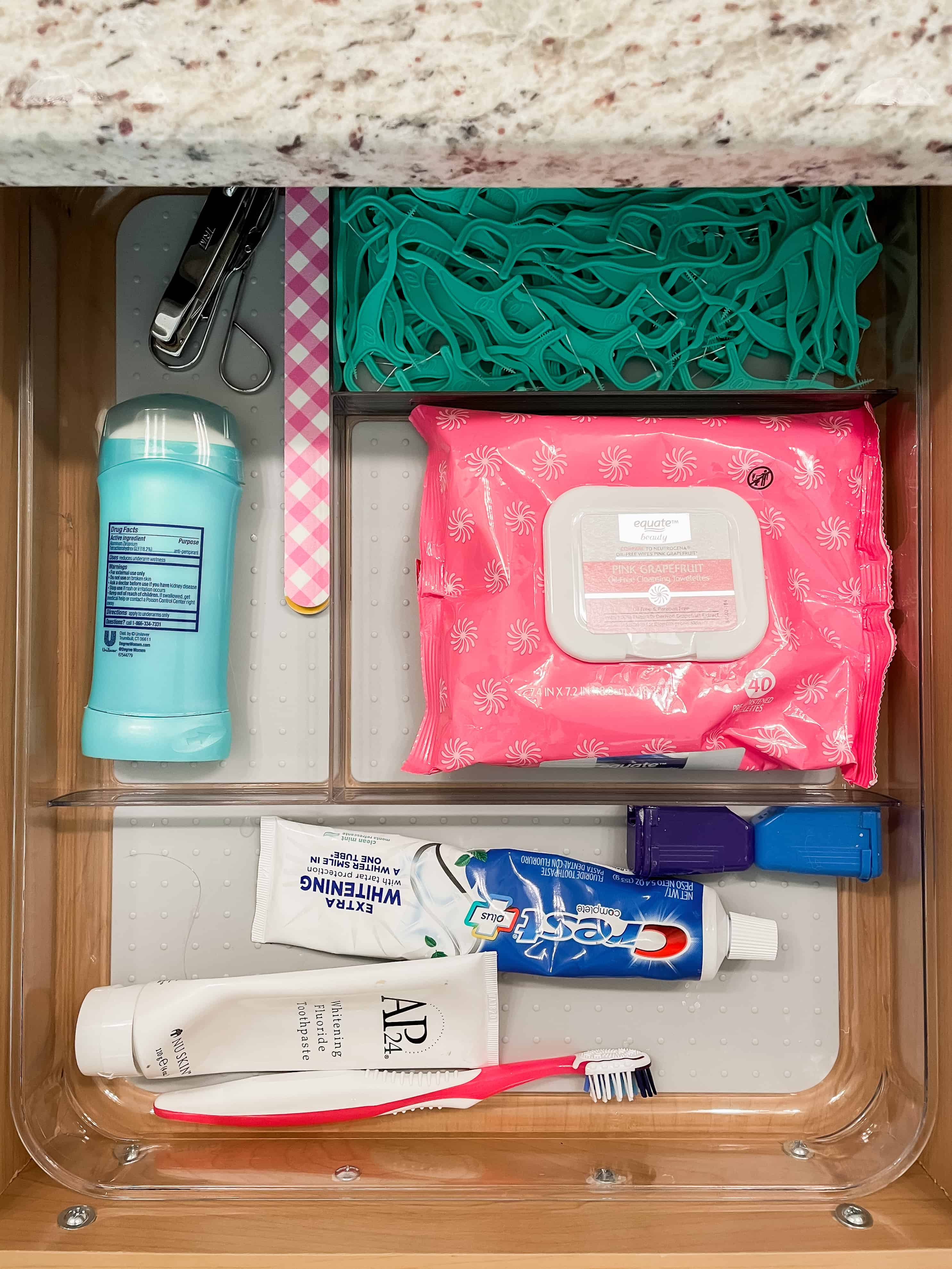 Bathroom organization. clear drawer organizer with toothpaste, deodorant, tooth flossers and makeup remover cloths.