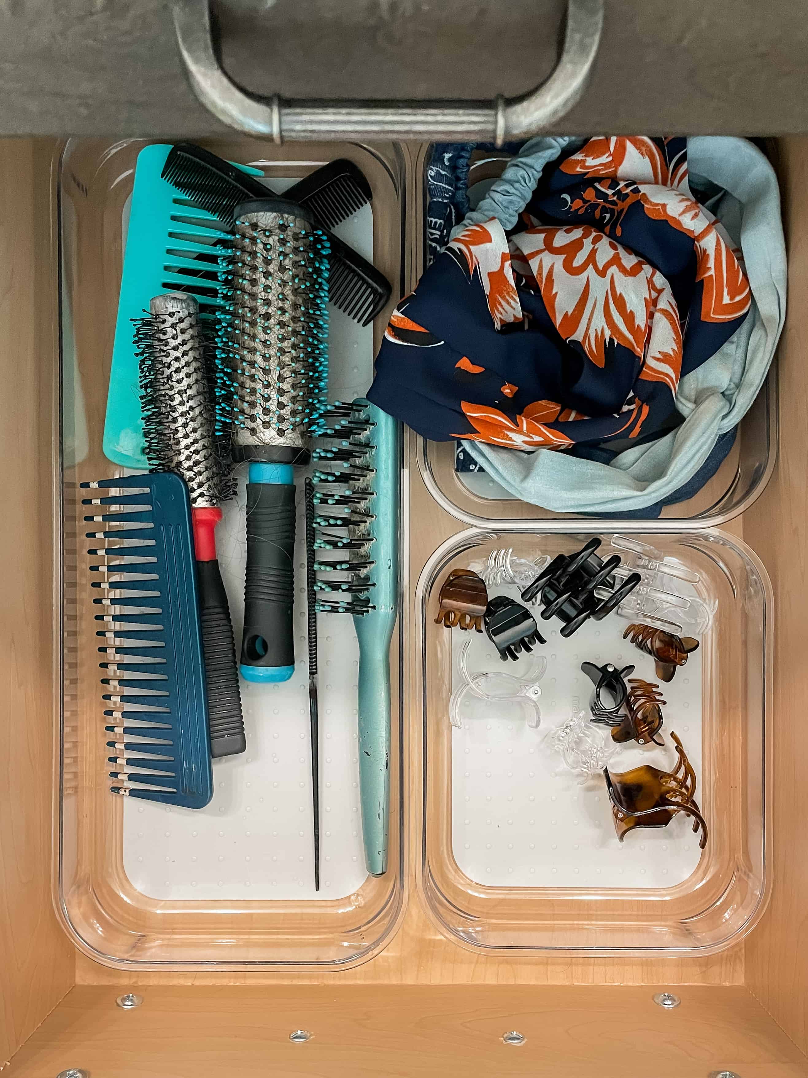 drawer organization ideas with clear bins holding brushes, headbands and claw clips.