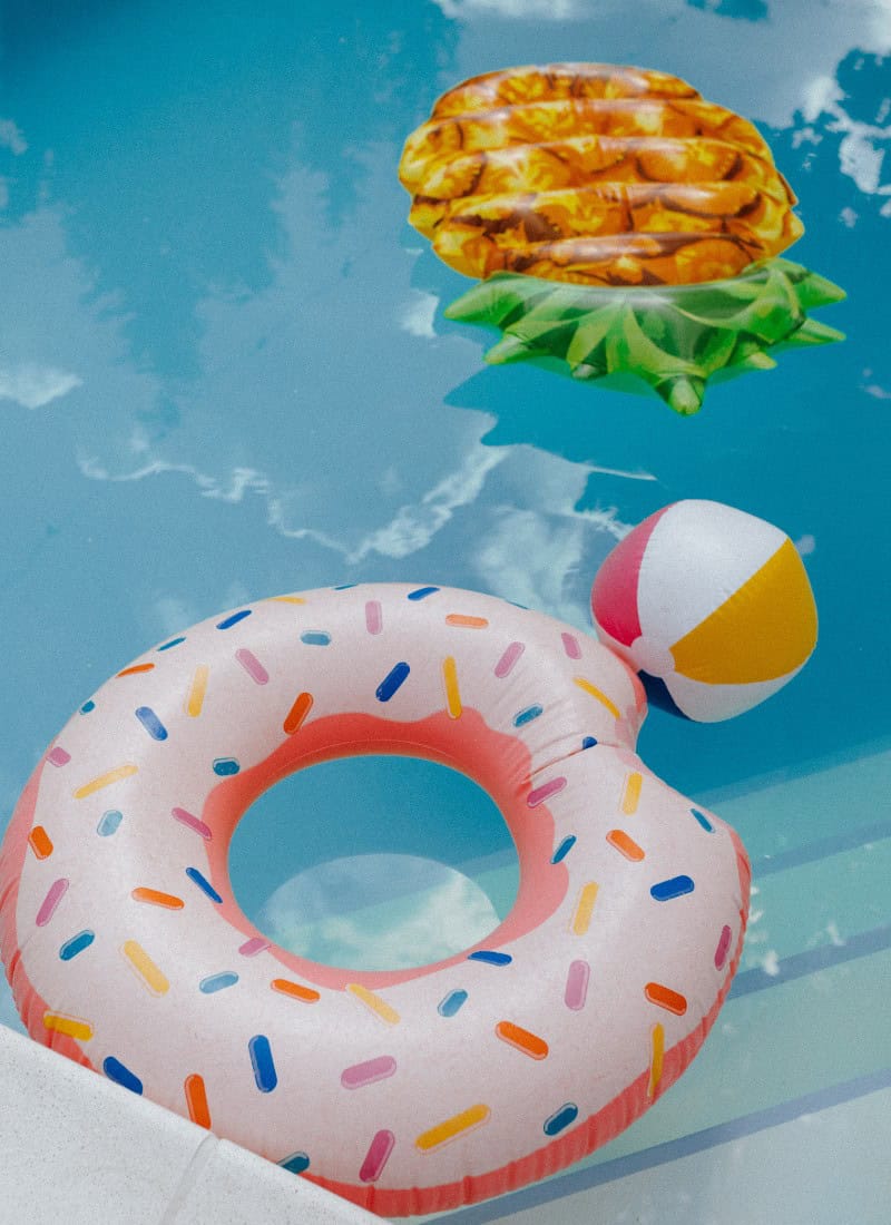 summer fun ideas for kids pool with donut pool float, beach ball and pineapple shaped pool float