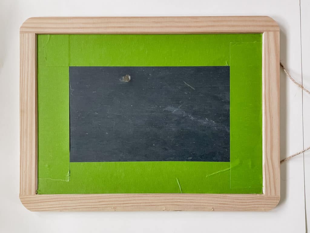 Rectangle chalkboard with wood frame. Green tape around inner edges of frame.