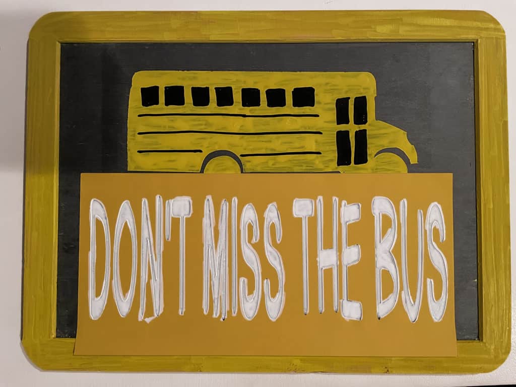 Rectangle chalkboard with yellow school bus and stencil that says don't miss the bus