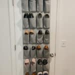 grey hanging shoe bag on white door filled with shoes