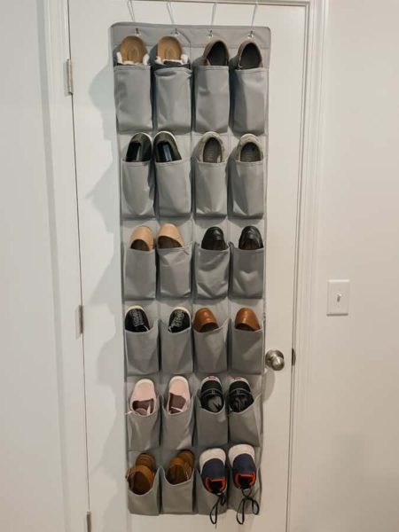 grey hanging shoe bag on white door filled with shoes