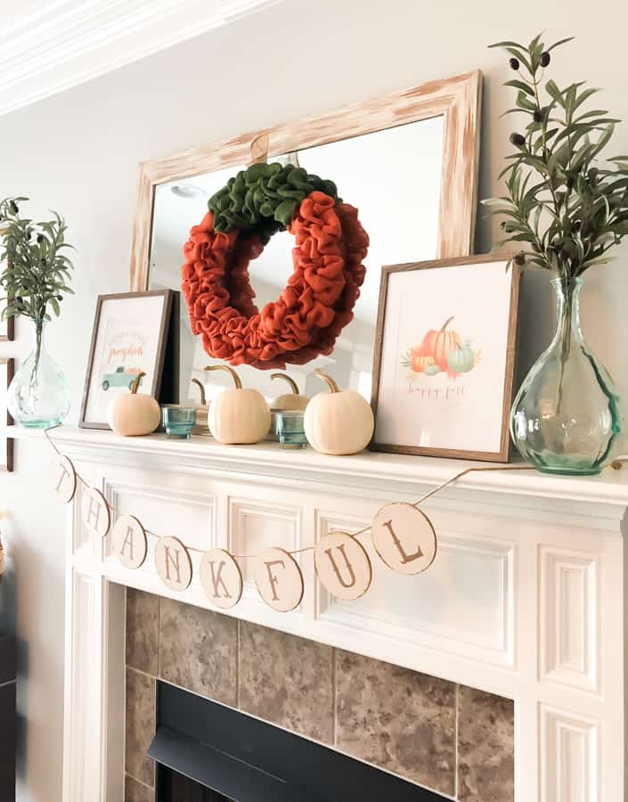 Fall mantel with mirror, orange burlap wreath, white pumpkins and framed fall prints. 