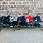 brick wall with black metal shoe rack filled with tennis shoes on concrete surface