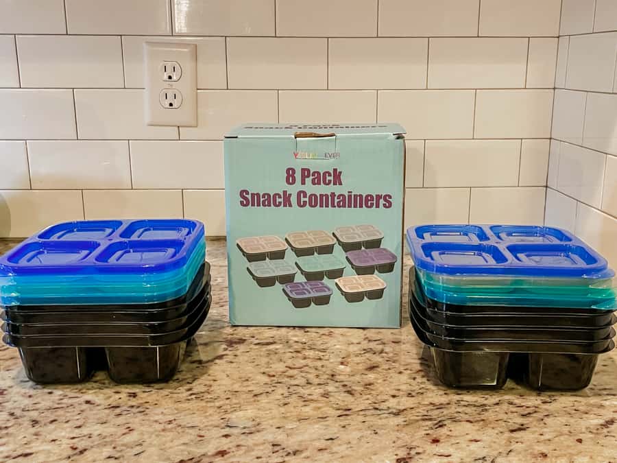 cottage keeping white backsplash with blue box that says 8 pack snack containers. black containers with blue lids on both sides of box.