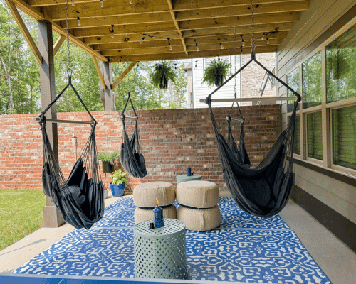 Covered back porch decor grey hanging hammock chairs with blue and white rug.
