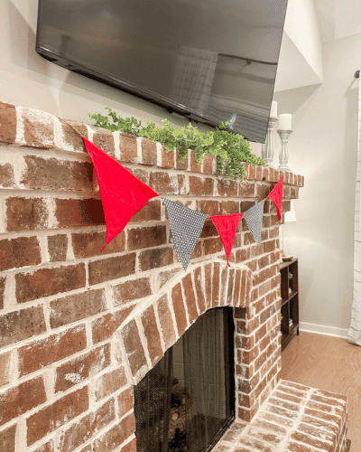 patriotic decoration of red white and blue garland hung on brick fireplace mantle