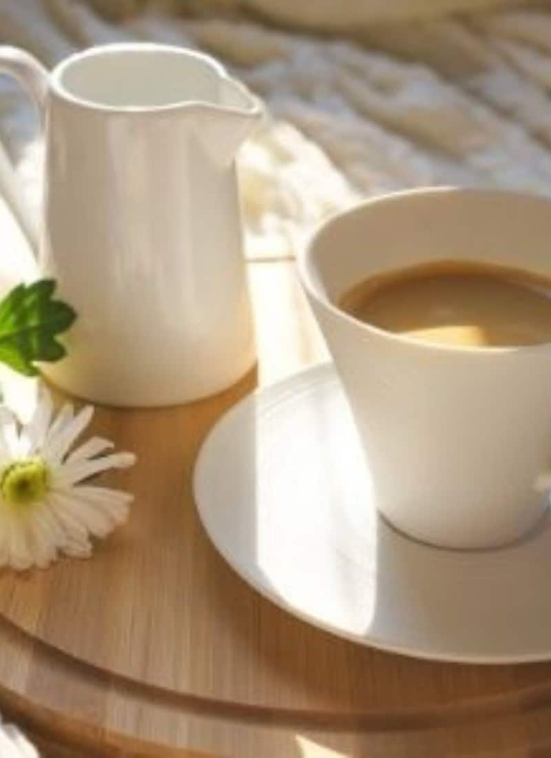 cottage keeping photo with white coffee mug on a saucer with coffee sitting beside a small pitcher of milk