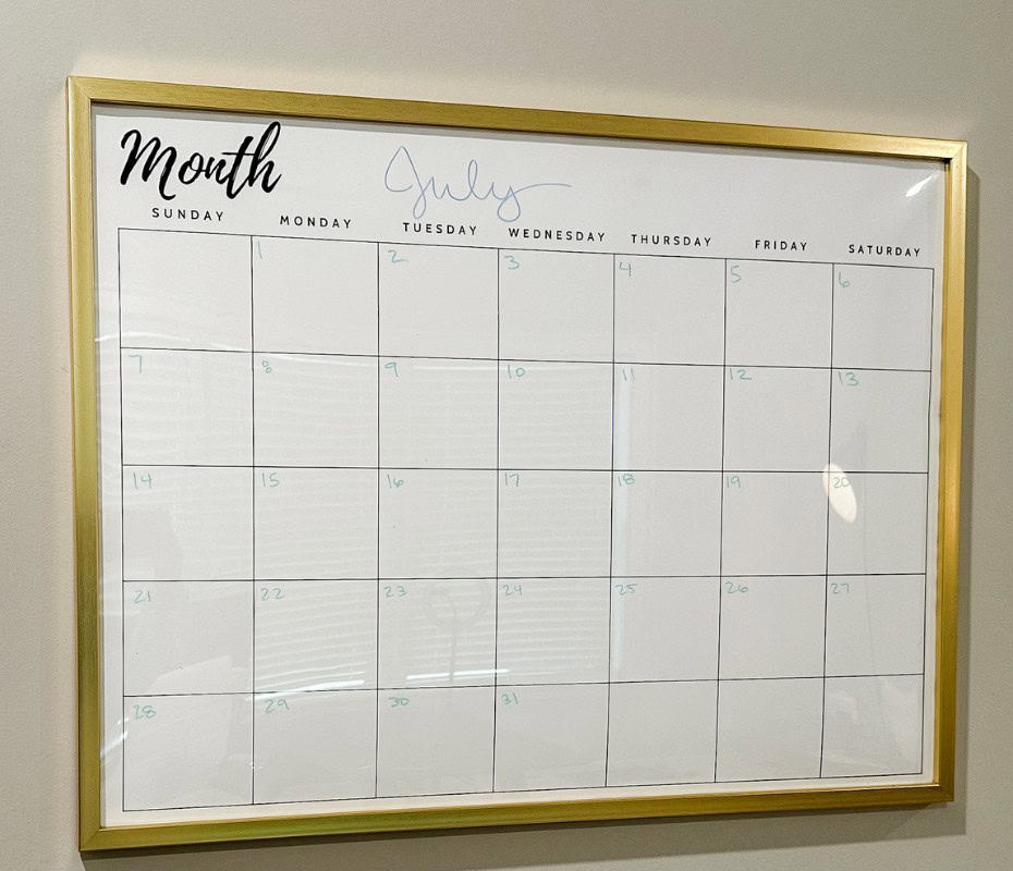 diy large wall calendar with gold frame hanging on grey wall.