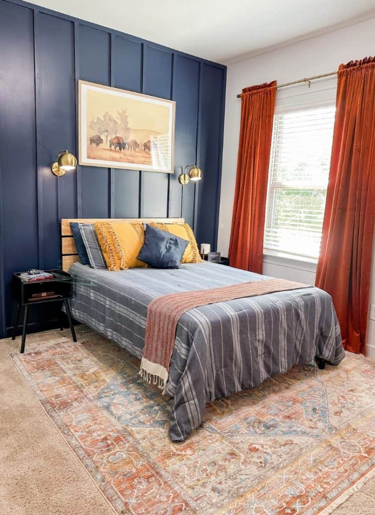 modern bedroom decor blue accent wall with large framed buffalo picture. full size bed with blue and white striped bedding with yellow accent pillows.