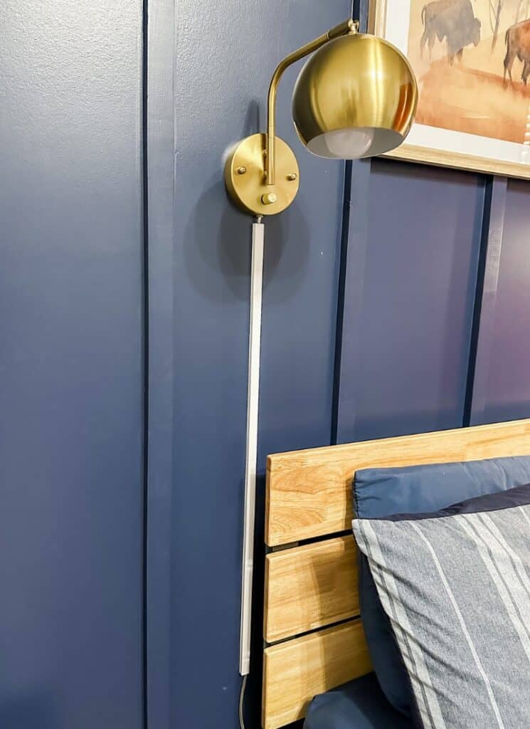 blue wall with white cord cover hanging behind a light wood headboard.