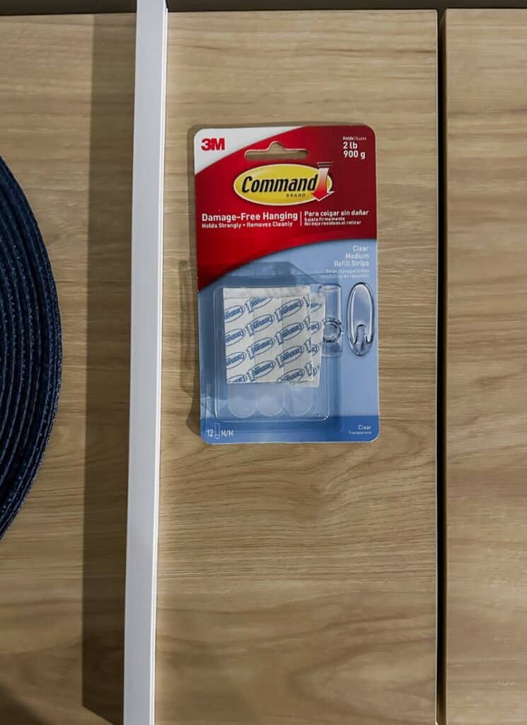 light cord cover and a pack of command strips for wall hooks on a light wood surface