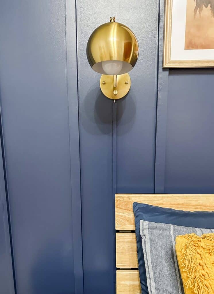 blue wall with gold wall sconce. cover light cords on a wall with this paintable cord cover product.