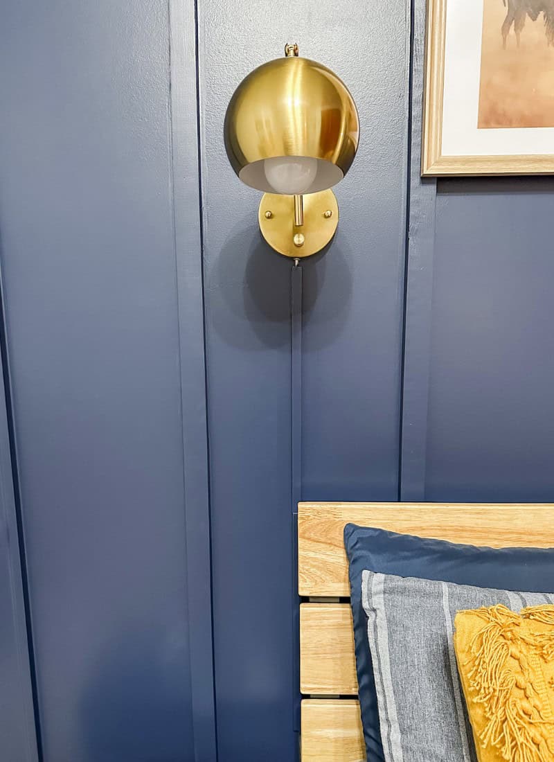 blue wall with gold wall sconce. cover light cords on a wall with this paintable cord cover product.