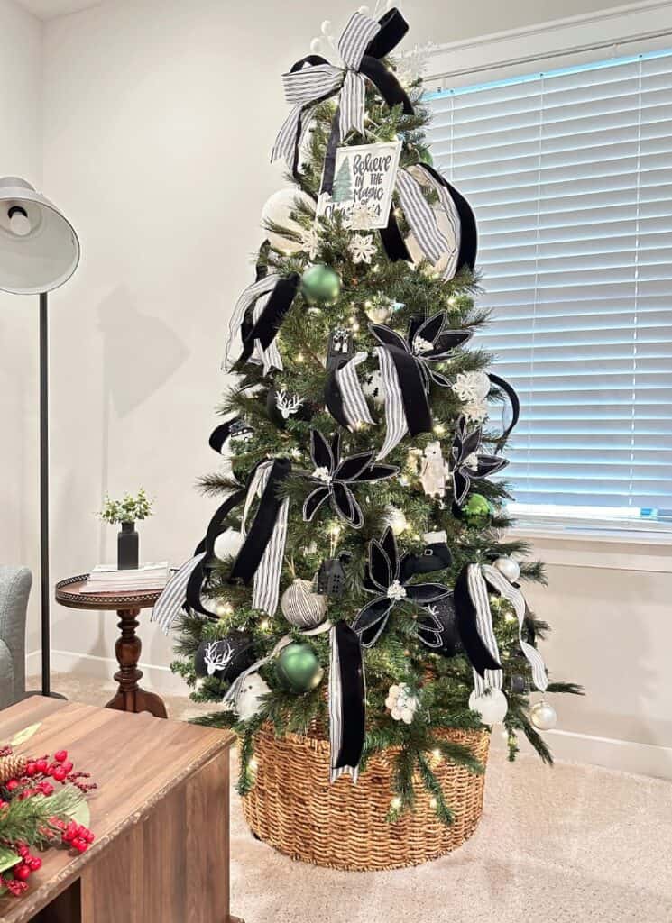 Green Christmas tree decorated with black and white ribbon and ornaments.